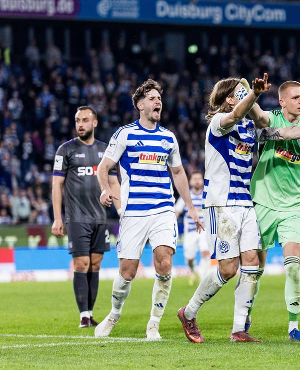 Ein Fan des MSV Duisburg wird von den Profis vom Feld geschoben.