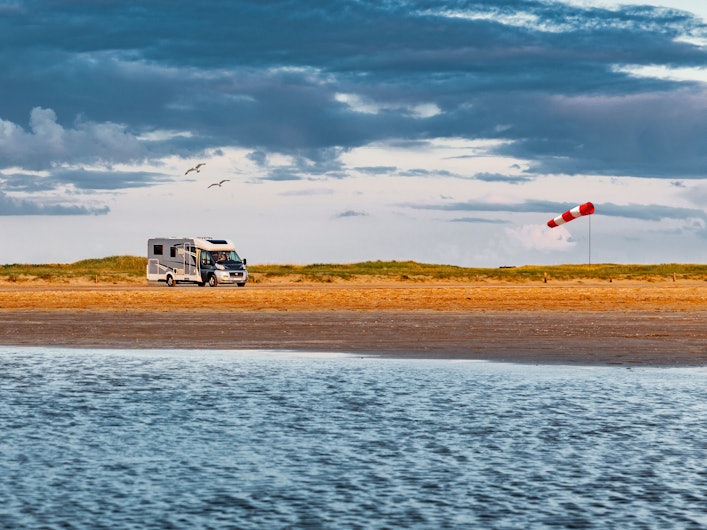 Wohnmobil fährt über eine Straße am Meer auf Romo