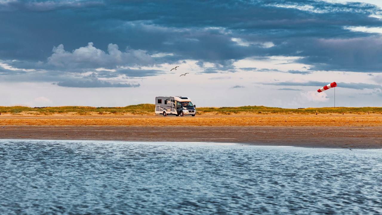 Wohnmobil fährt über eine Straße am Meer auf Romo