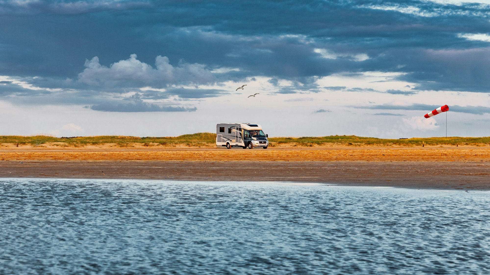 Wohnmobil fährt über eine Straße am Meer auf Romo