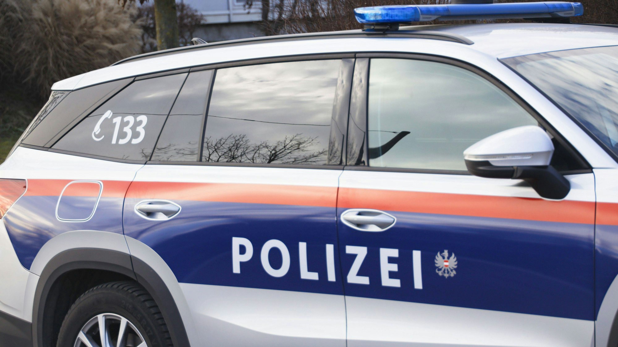 Polizeiauto mit Blaulicht und Notrufnummer 133