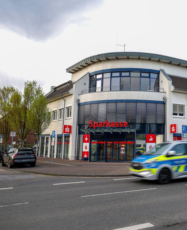 Ein Polizeiauto fährt an einer Sparkassenfiliale vorbei. Ein vermutlich bewaffneter Mann hat mit dem Betreten einer Sparkassenfiliale in Rommerskirchen bei Neuss einen Großeinsatz der Polizei ausgelöst. Nach etwa zwei Stunden habe der Mann sich widerstandslos festnehmen lassen, sagte eine Polizeisprecherin.