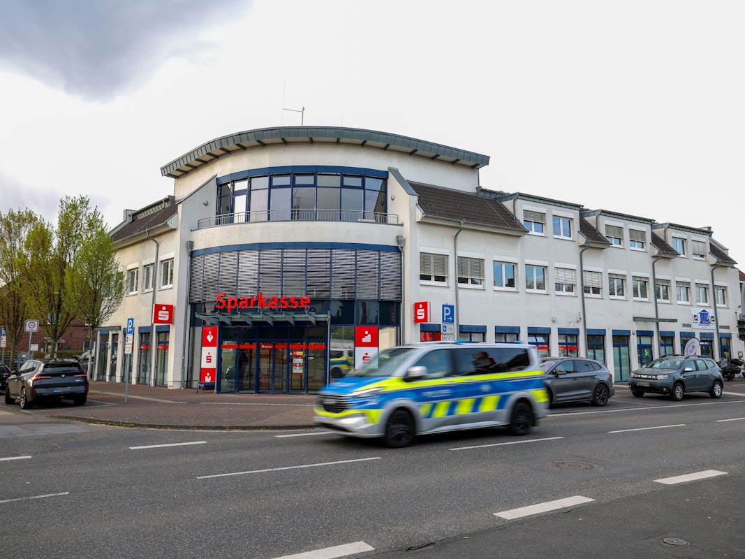 Ein Polizeiauto fährt an einer Sparkassenfiliale vorbei. Ein vermutlich bewaffneter Mann hat mit dem Betreten einer Sparkassenfiliale in Rommerskirchen bei Neuss einen Großeinsatz der Polizei ausgelöst. Nach etwa zwei Stunden habe der Mann sich widerstandslos festnehmen lassen, sagte eine Polizeisprecherin.