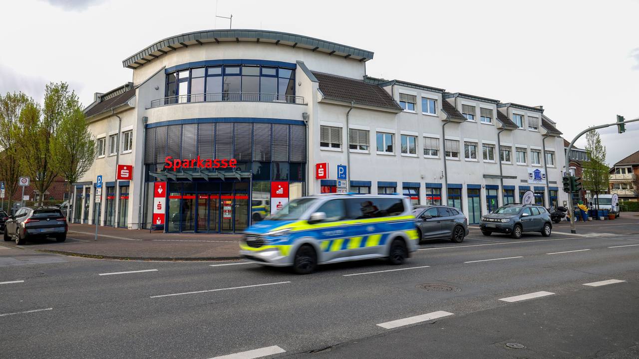 Ein Polizeiauto fährt an einer Sparkassenfiliale vorbei. Ein vermutlich bewaffneter Mann hat mit dem Betreten einer Sparkassenfiliale in Rommerskirchen bei Neuss einen Großeinsatz der Polizei ausgelöst. Nach etwa zwei Stunden habe der Mann sich widerstandslos festnehmen lassen, sagte eine Polizeisprecherin.