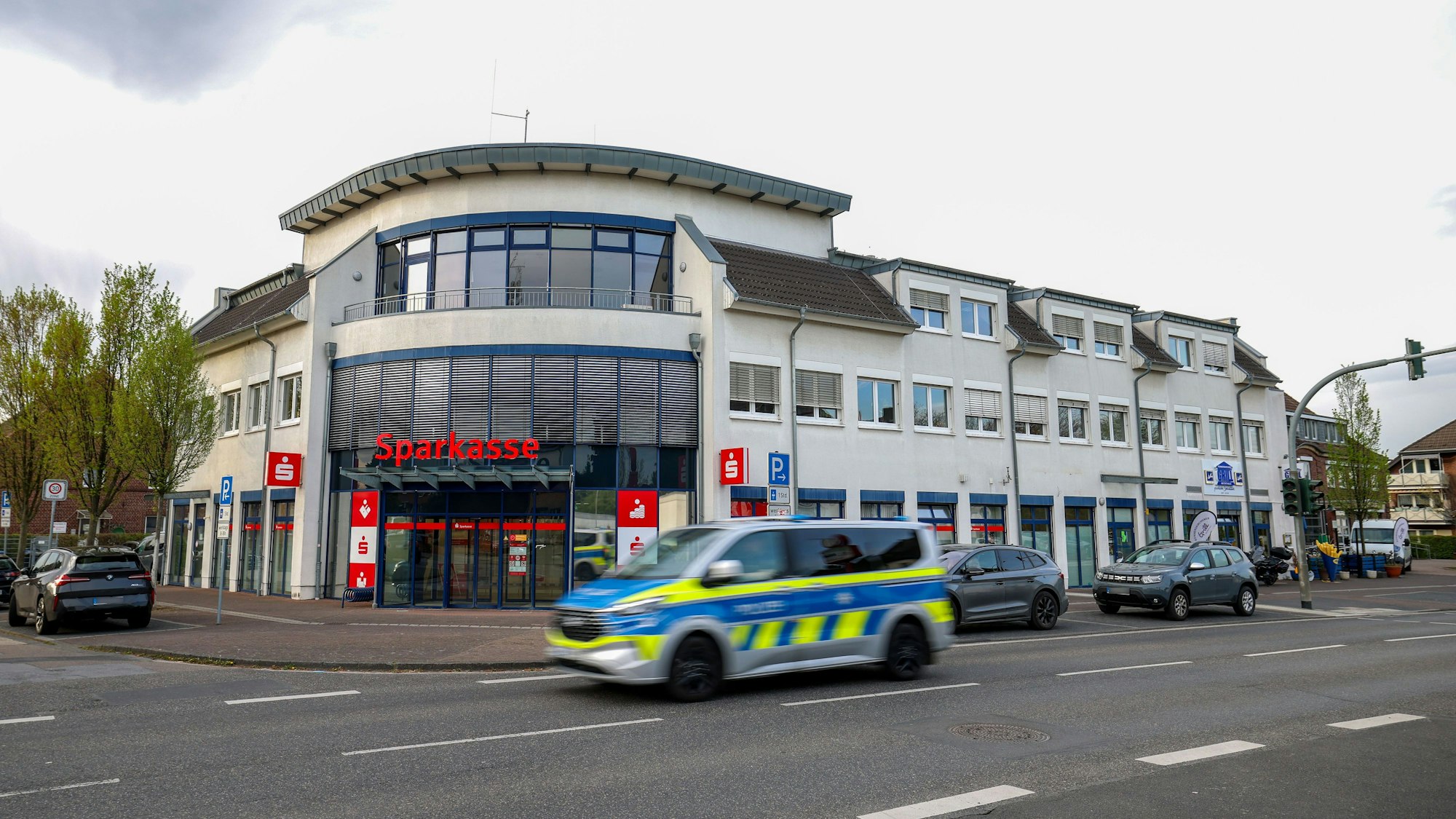 Ein Polizeiauto fährt an einer Sparkassenfiliale vorbei. Ein vermutlich bewaffneter Mann hat mit dem Betreten einer Sparkassenfiliale in Rommerskirchen bei Neuss einen Großeinsatz der Polizei ausgelöst. Nach etwa zwei Stunden habe der Mann sich widerstandslos festnehmen lassen, sagte eine Polizeisprecherin.
