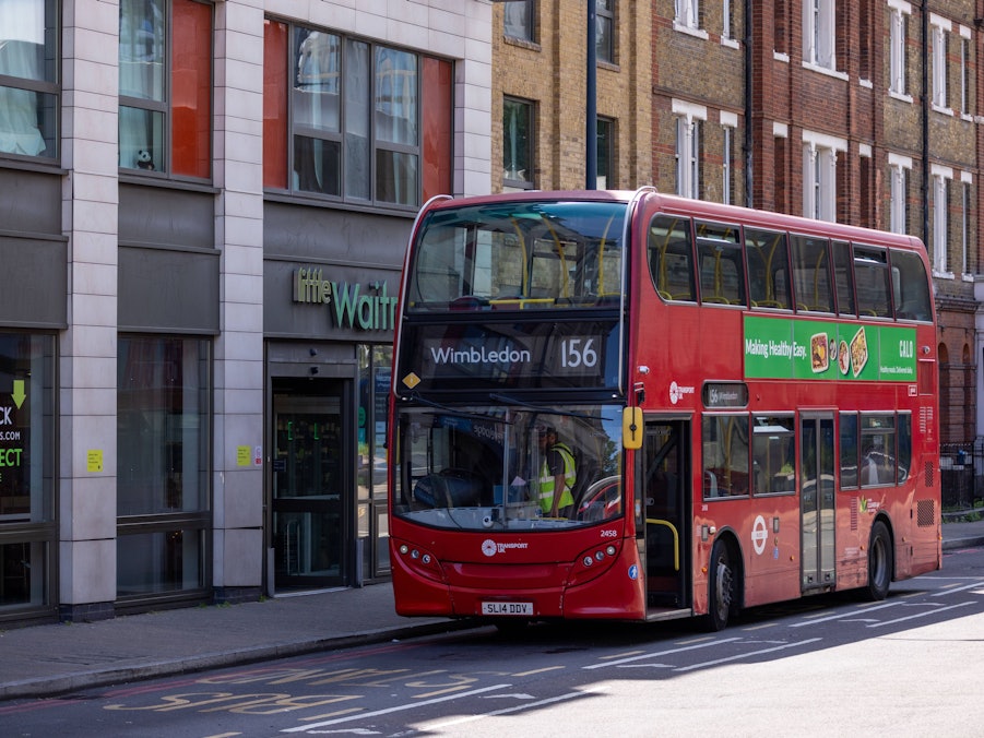 Roter Doppeldeckerbus fährt an Gebäuden vorbei