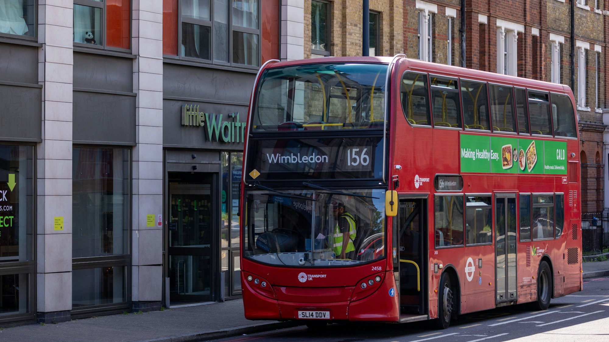 Roter Doppeldeckerbus fährt an Gebäuden vorbei