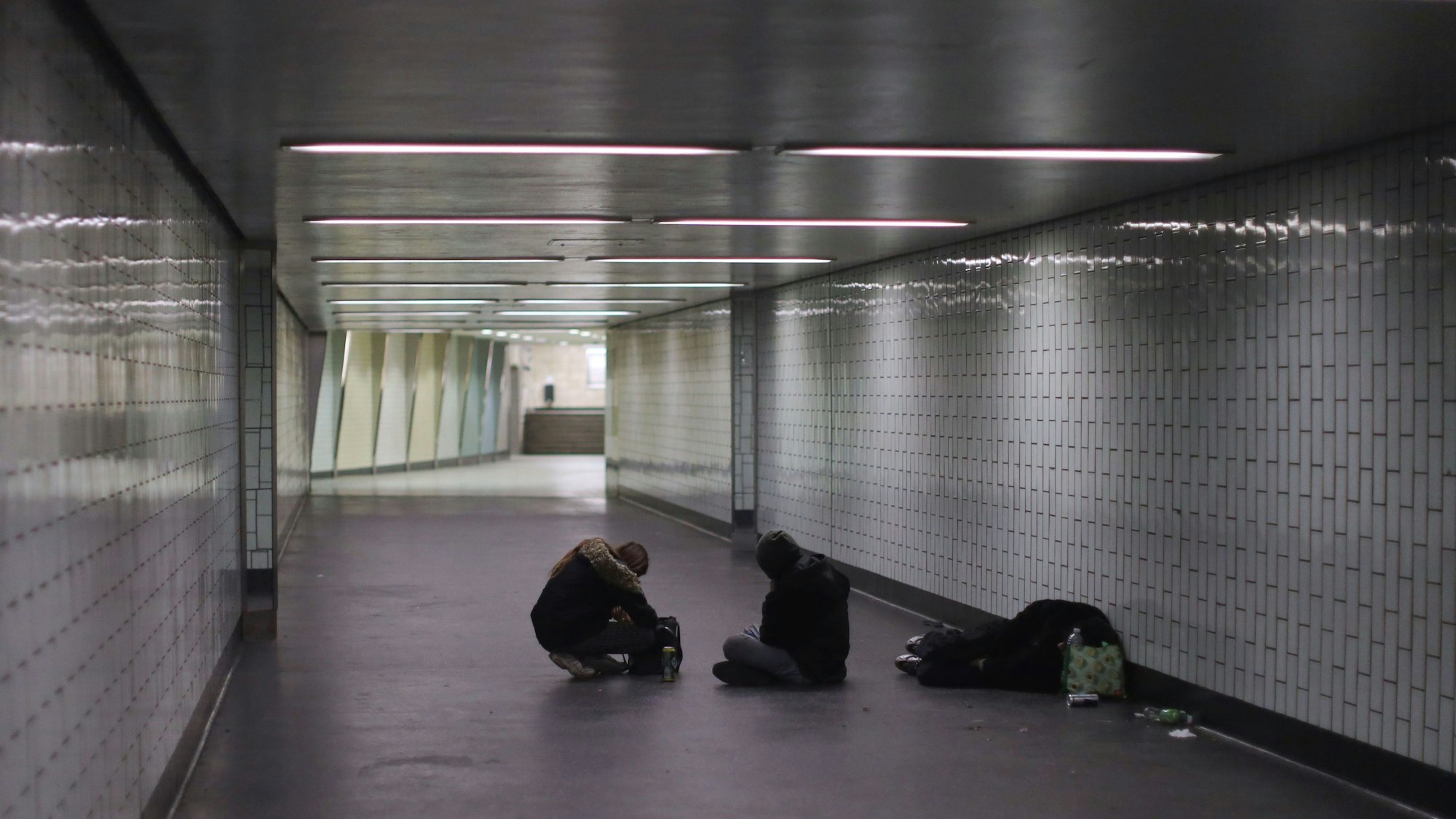 An der Haltestelle Appellhofplatz liegen beziehungsweise sitzen Menschen auf dem Boden.