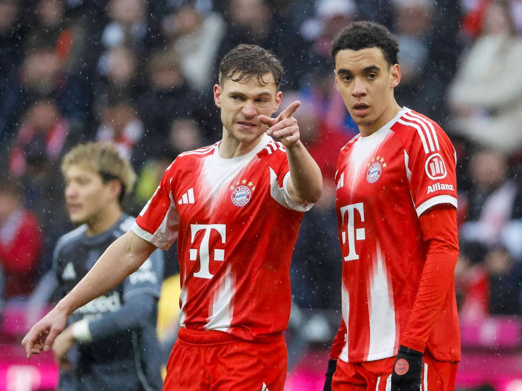 Joshua Kimmich zeigt Jamal Musiala etwas auf dem Platz.