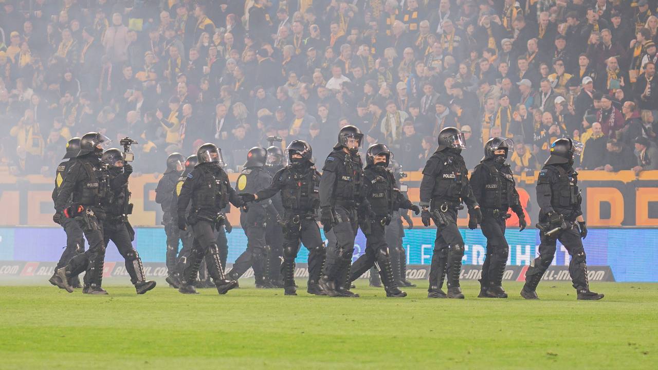 Beim Spiel von Dynamo Dresden stehen Polizisten in Einsatzmontur auf dem Rasen.