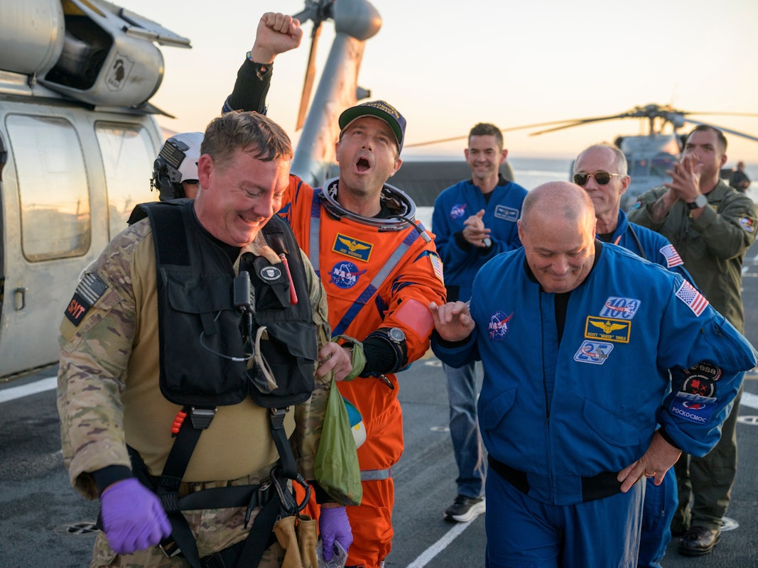 Astronaut Reid Wiseman, Kommandant von Artemis II, wird vom Flugdeck begleitet.