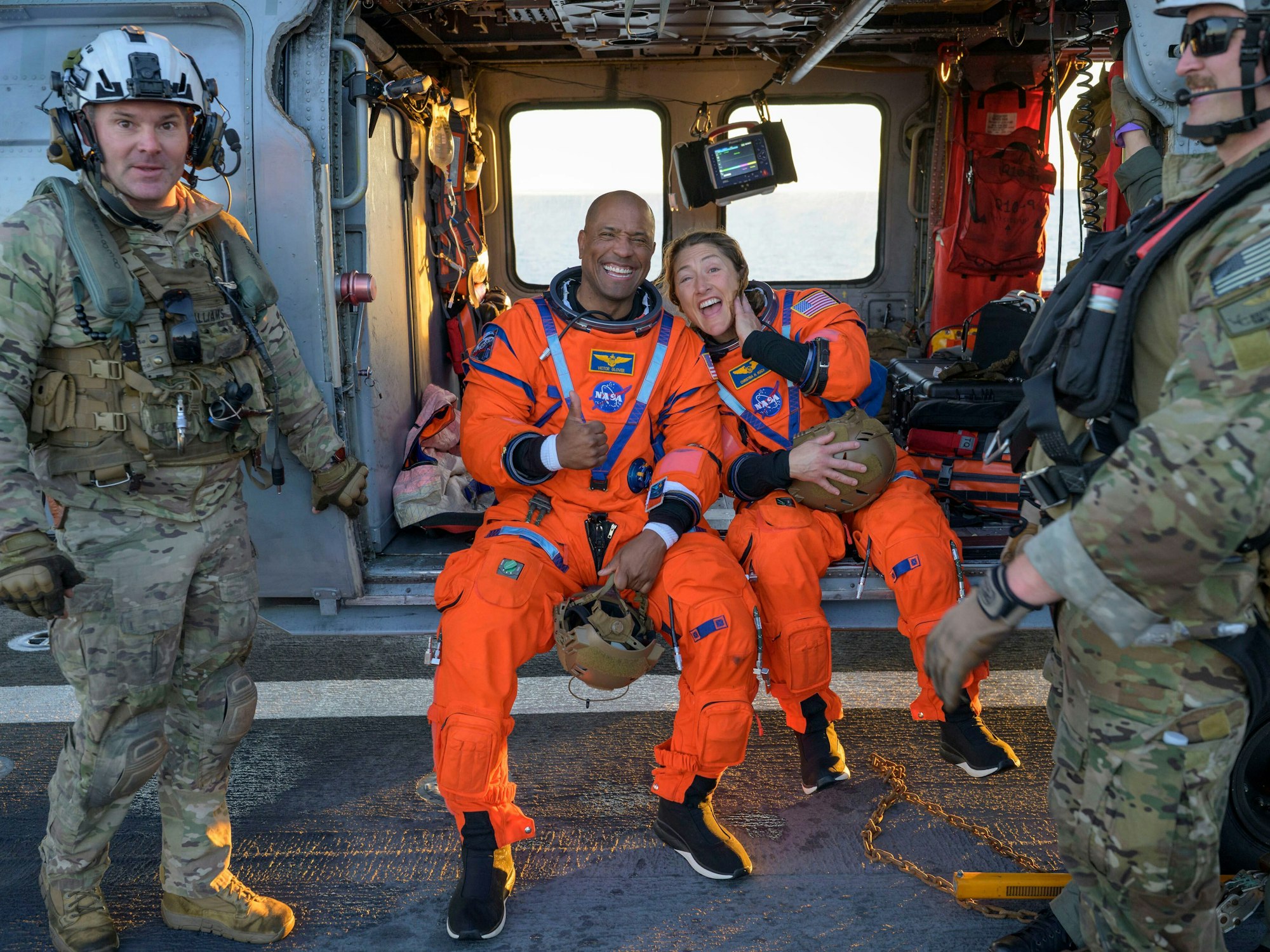 Die Astronauten Victor Glover, Artemis-II-Pilot (l) und Christina Koch, Artemis-II-Missionsspezialistin, sitzen auf einem MH-60 Seahawk der Navy auf dem Flugdeck der USS John P. Murtha.
