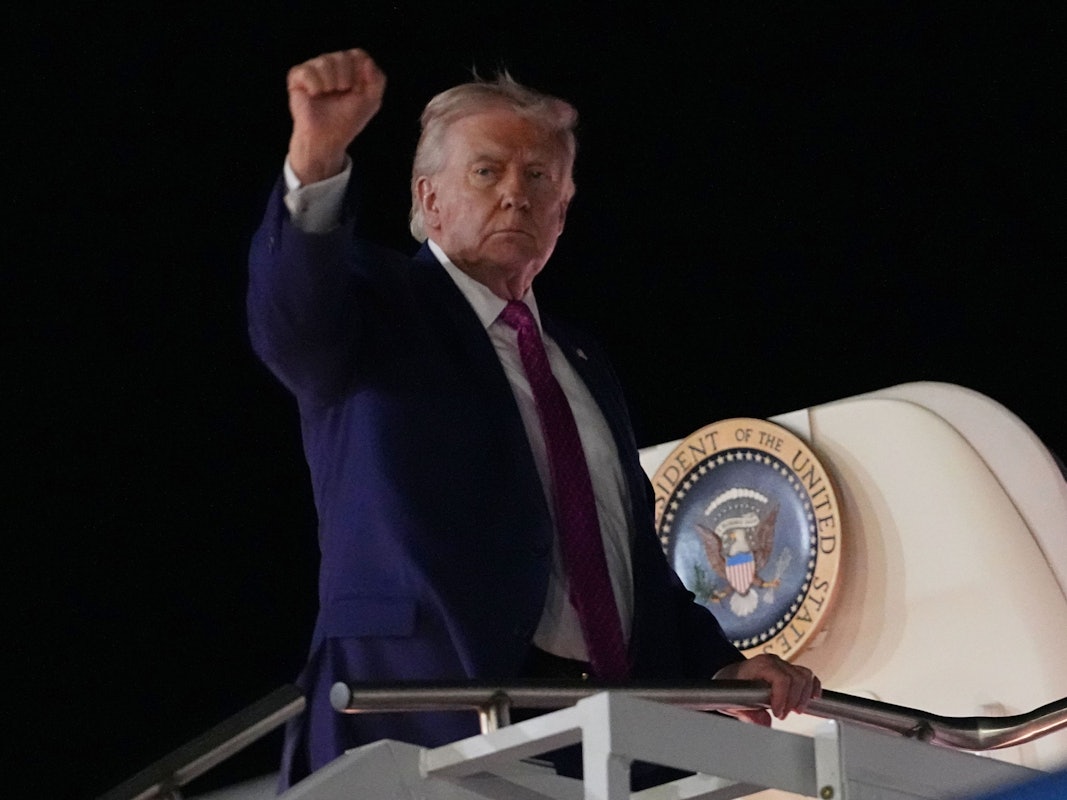 US-Präsident Donald Trump besteigt ein Flugzeug und zeigt eine geballte Faust.