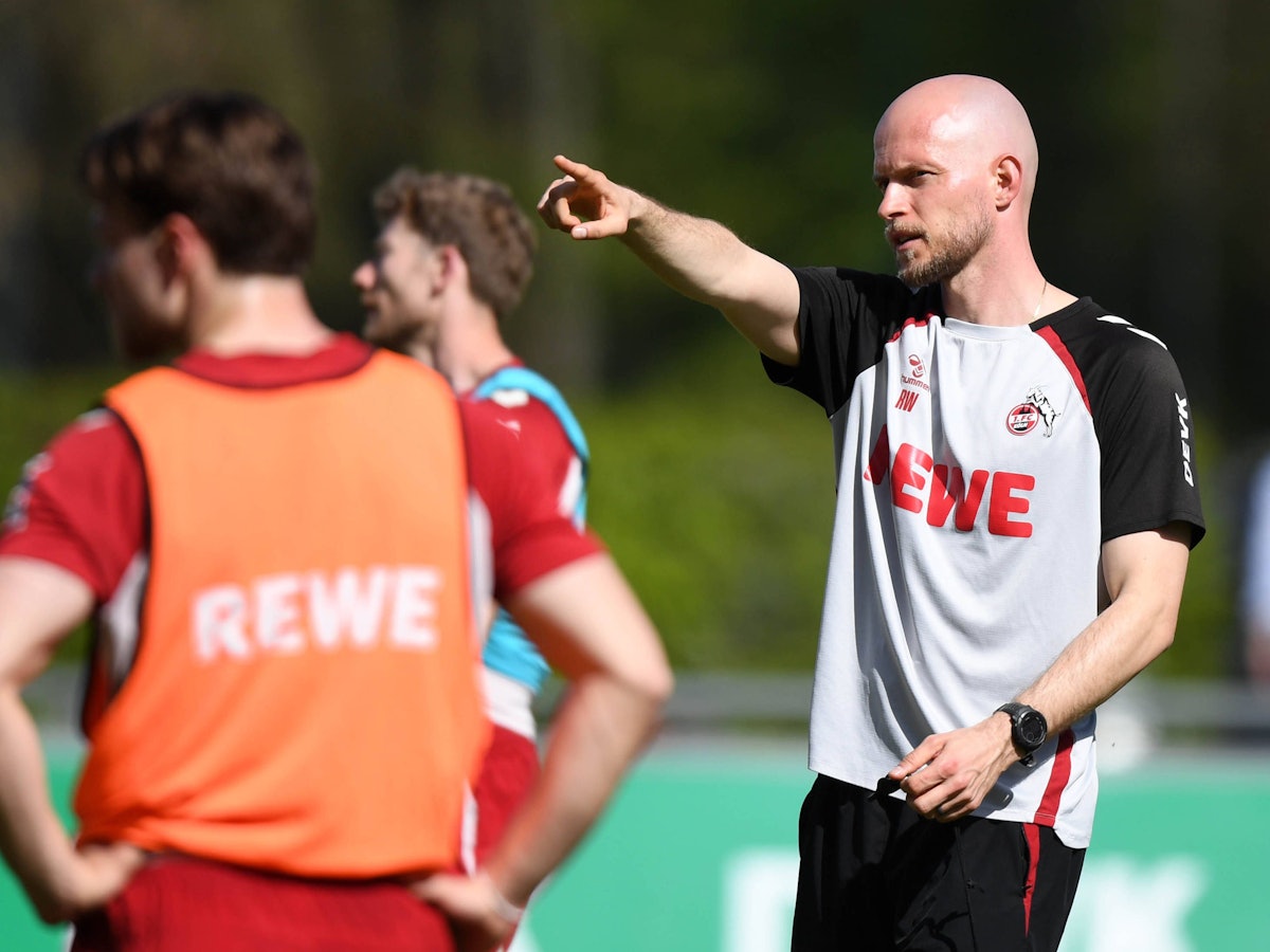 René Wagner gibt auf dem Trainingsplatz Anweisungen und zeigt in eine Richtung.