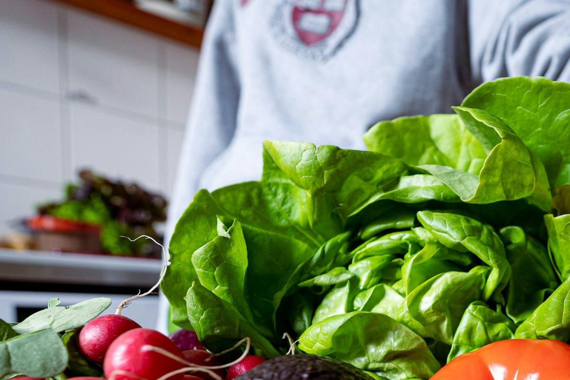 Eine Frau legt eine Paprika auf eine Ansammlung an Gemüse