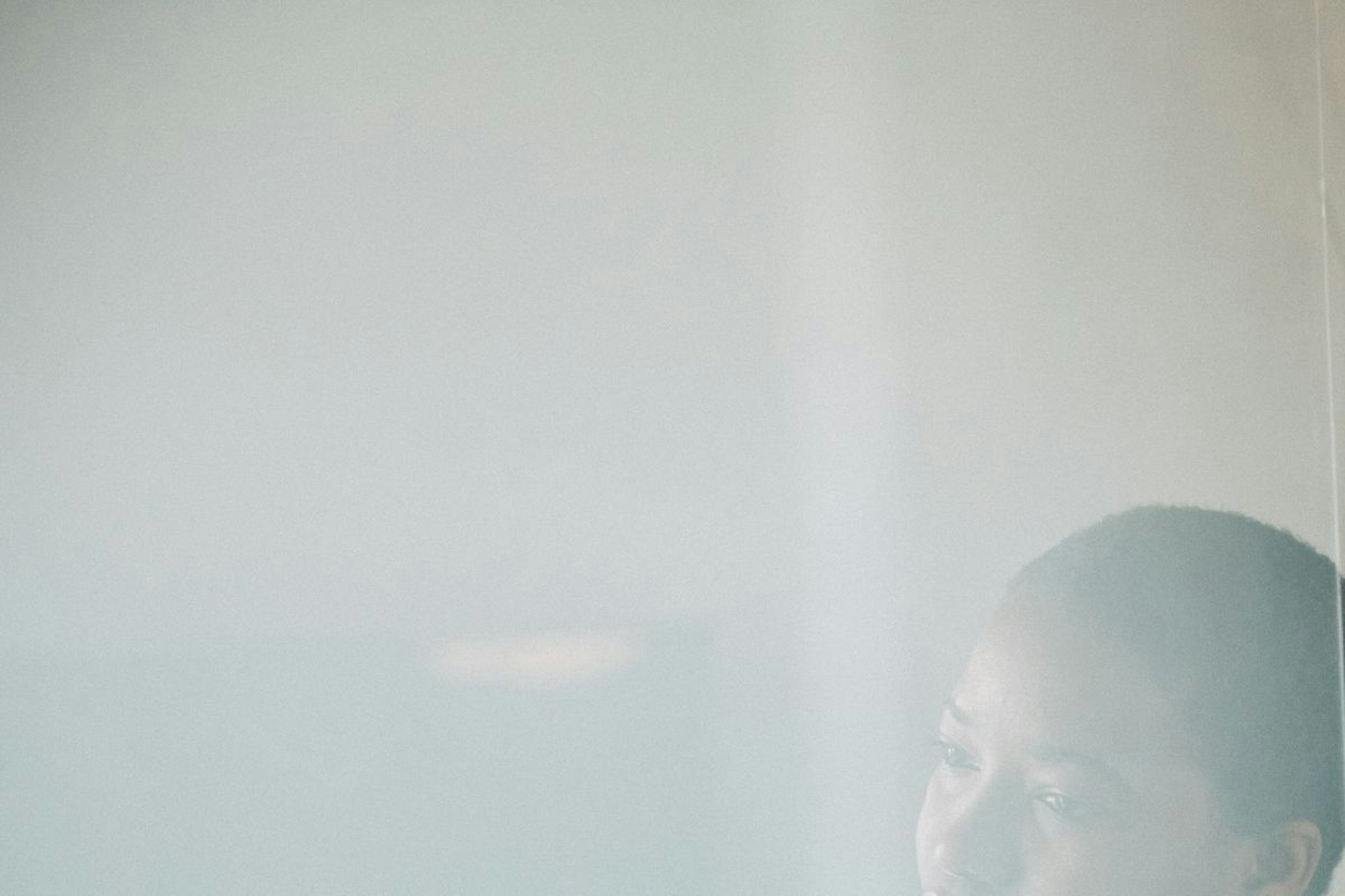 Eine junge Frau lehnt nachdenklich an einer Glaswand