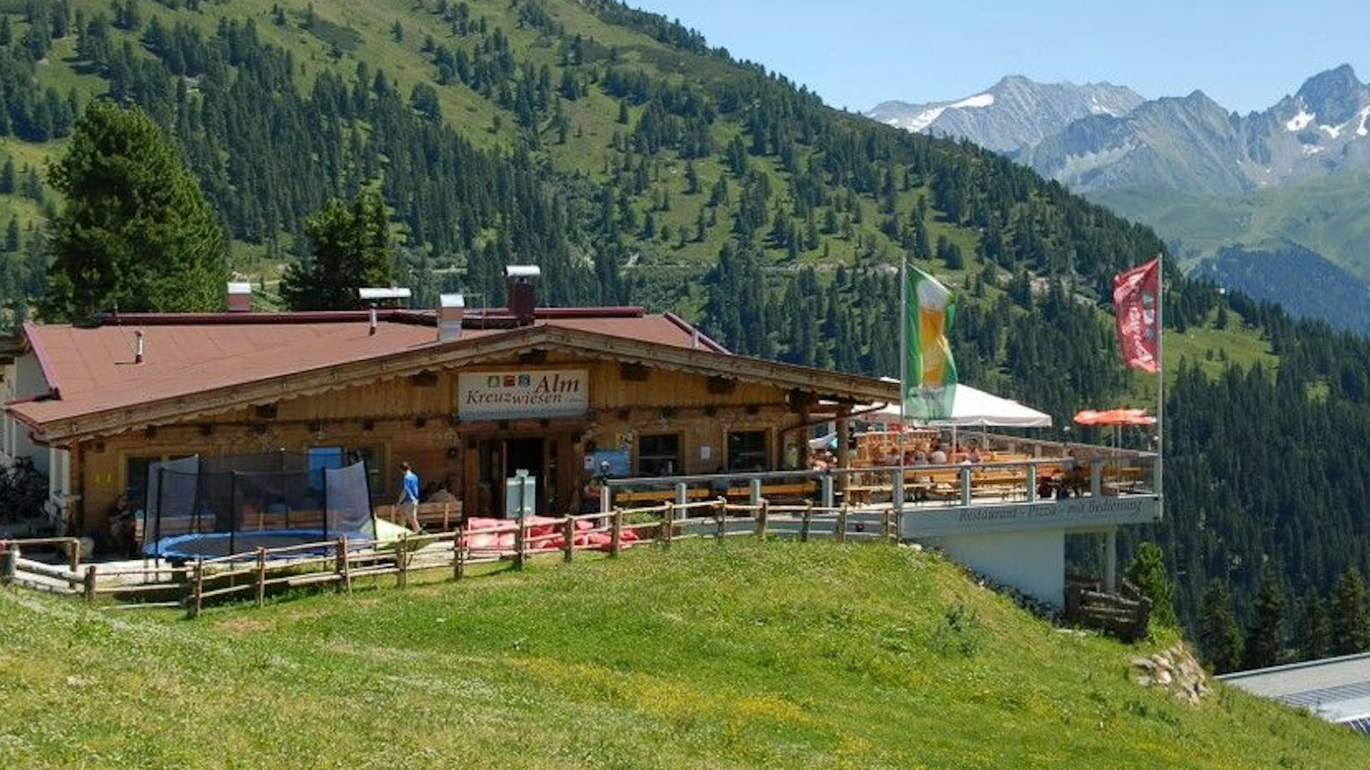 Eine Almhütte mit großer Sonnenterrasse und Blick auf die Berge