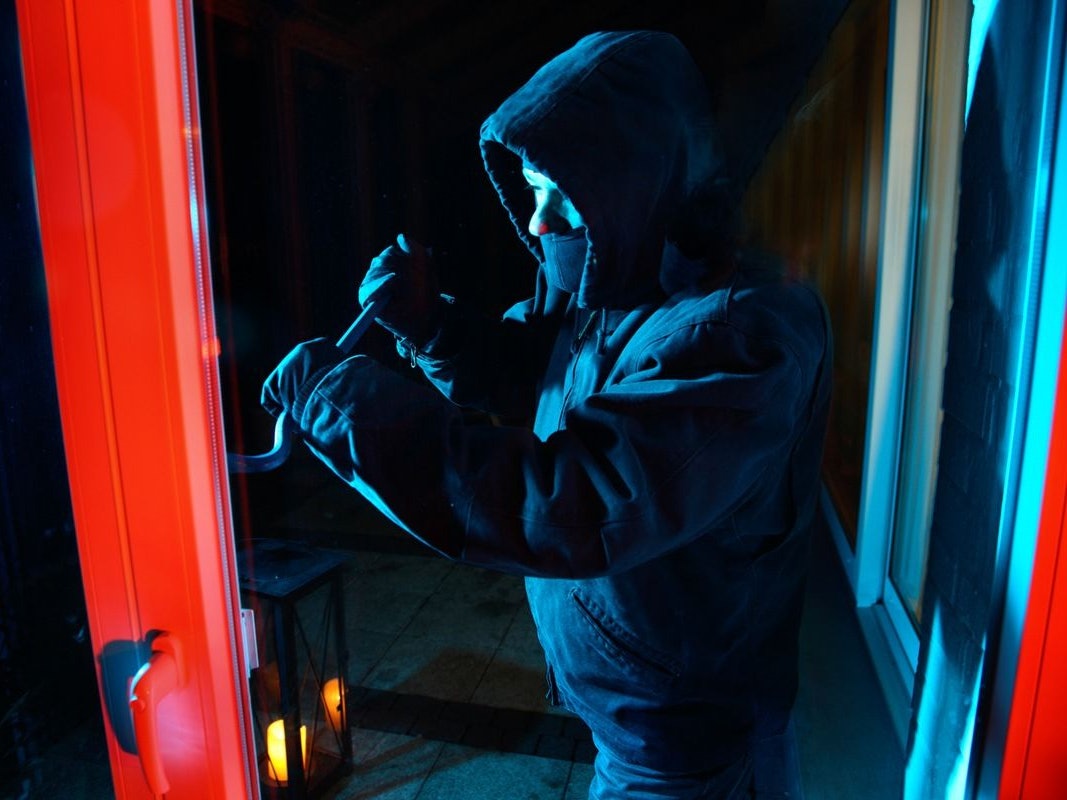 Einbrecher hebelt mit Kuhfuß ein Fenster auf.