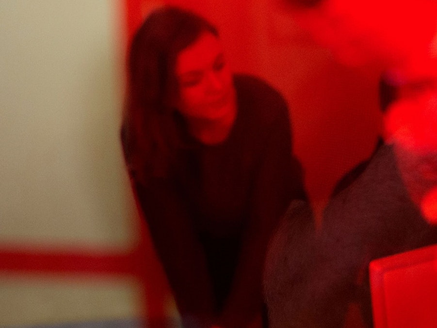 Eine Frau sitzt hinter einer rot bemalten Scheibe