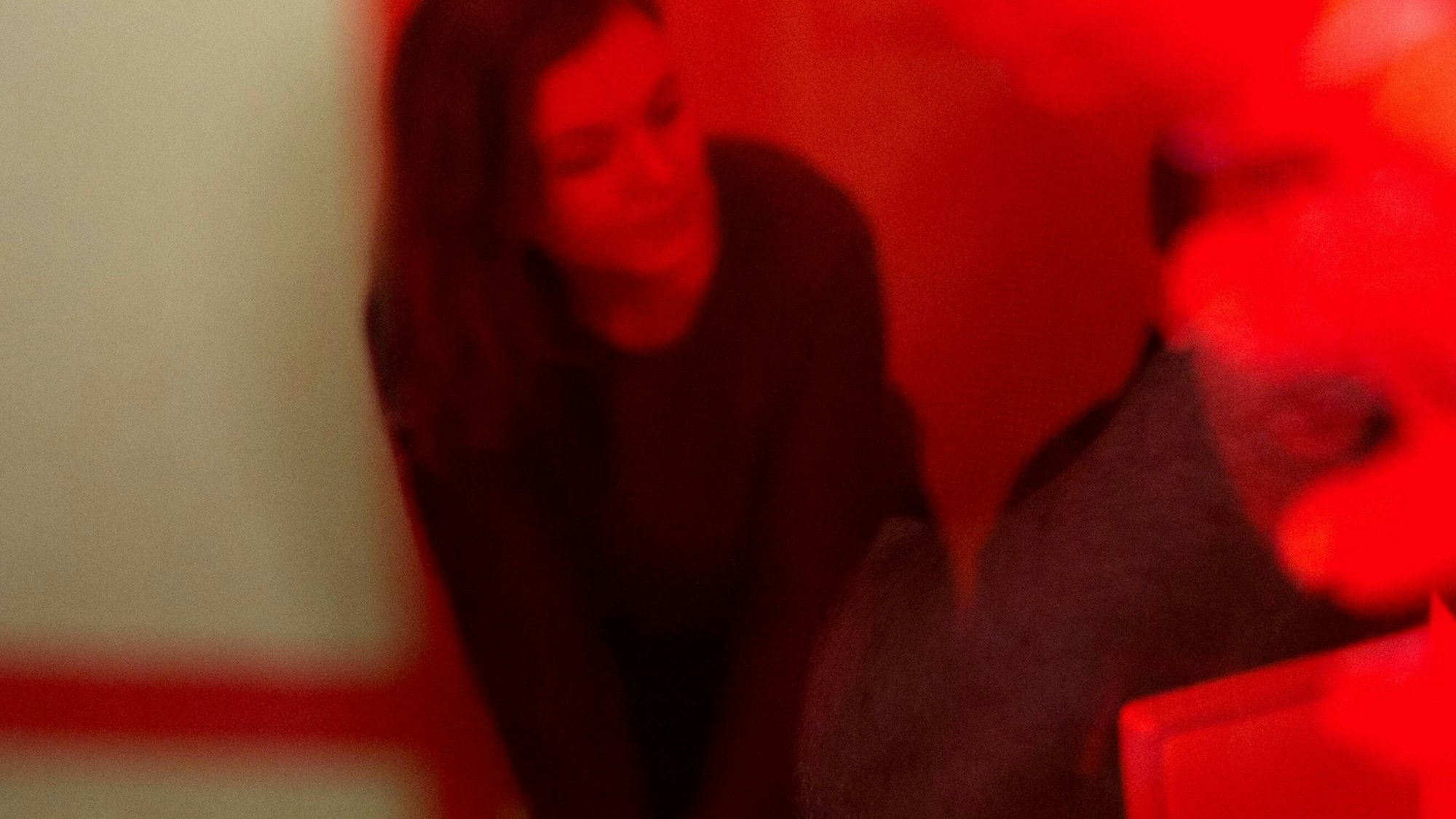 Eine Frau sitzt hinter einer rot bemalten Scheibe