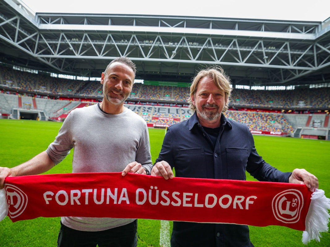Alexander Ende und Sven Mislintat posieren mit Fortuna-Düsseldorf-Schal in der Merkur-Spiel-Arena.