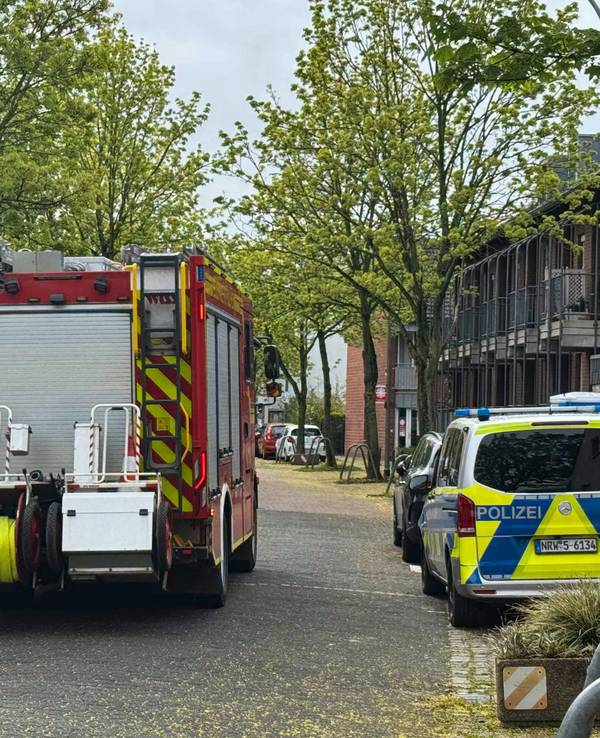 Ein Feuerwehr- und ein Polizeifahrzeug stehen auf einer Straße.