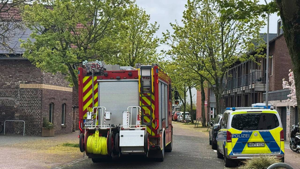Ein Feuerwehr- und ein Polizeifahrzeug stehen auf einer Straße.