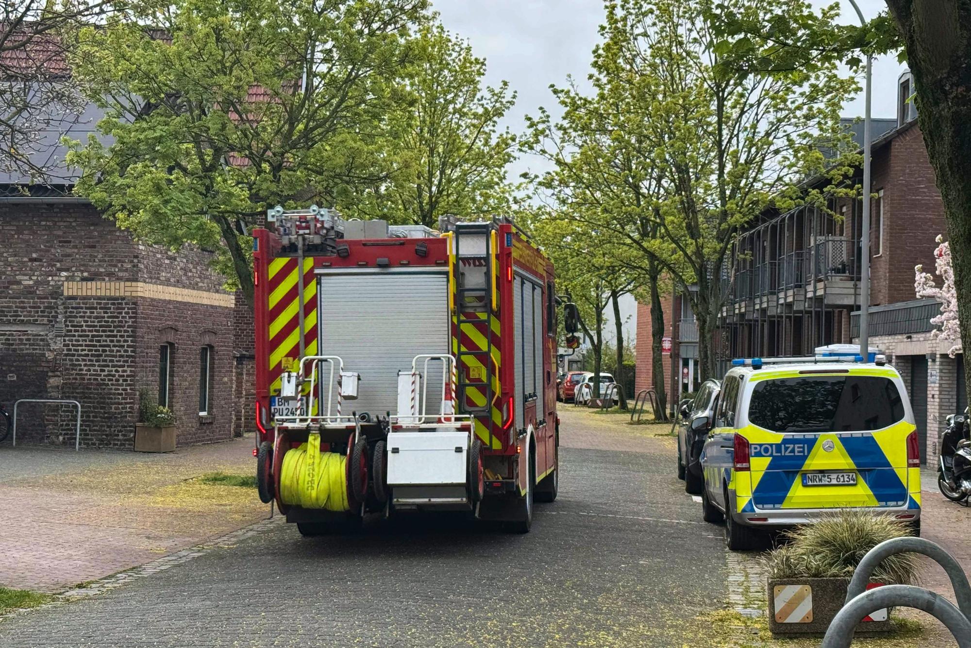 Ein Feuerwehr- und ein Polizeifahrzeug stehen auf einer Straße.