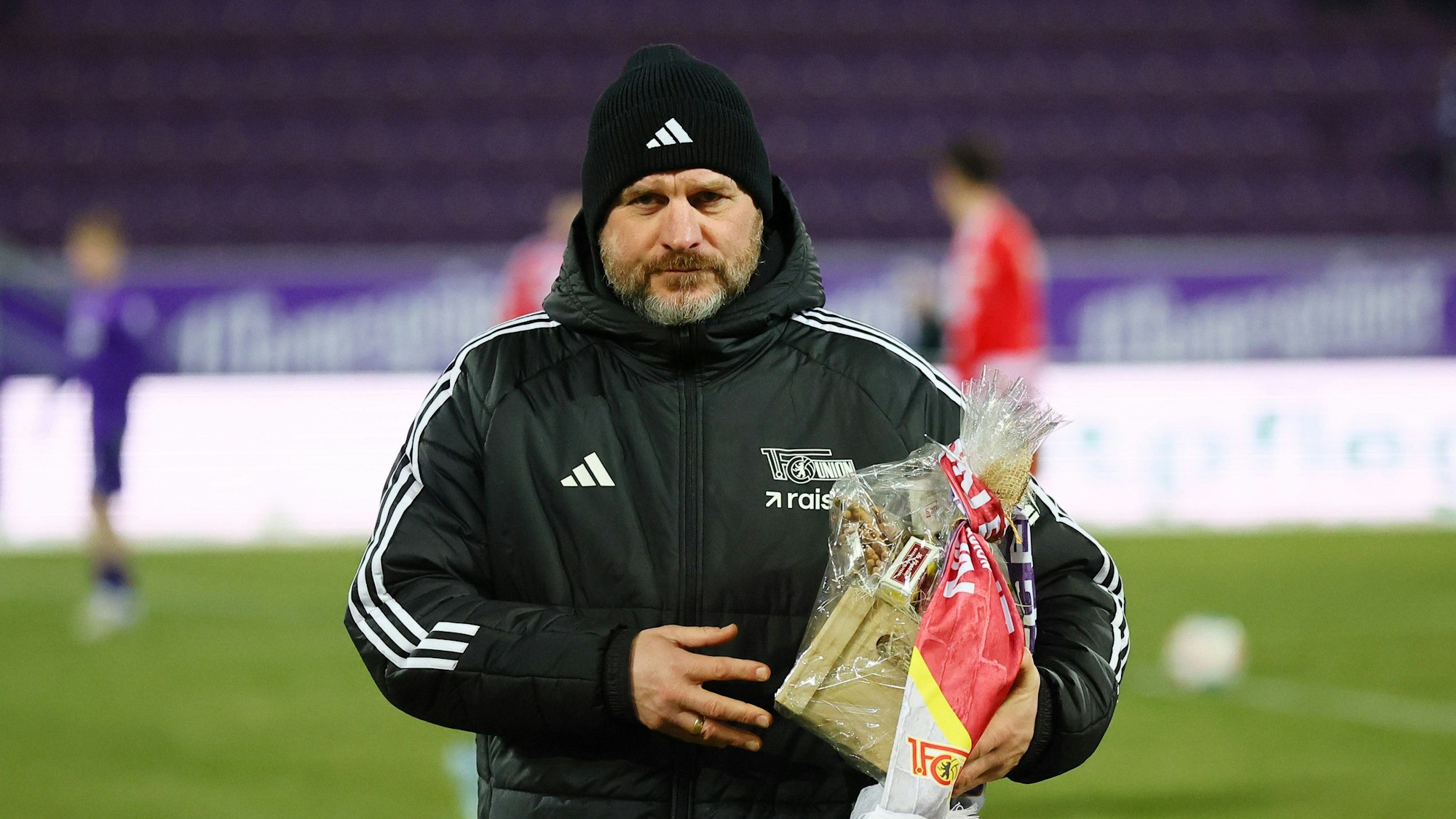 Steffen Baumgart bei einem Testspiel mit Fanartikeln in der Hand.