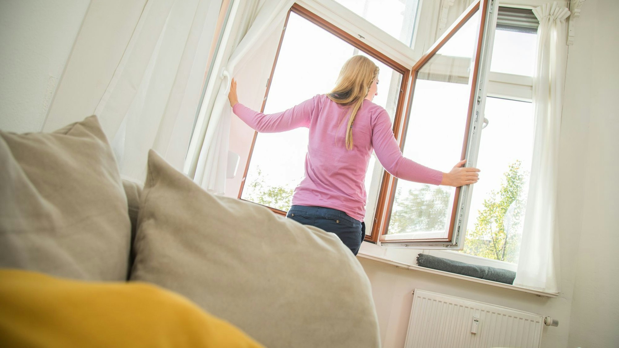 Eine Frau öffnet ein Fenster