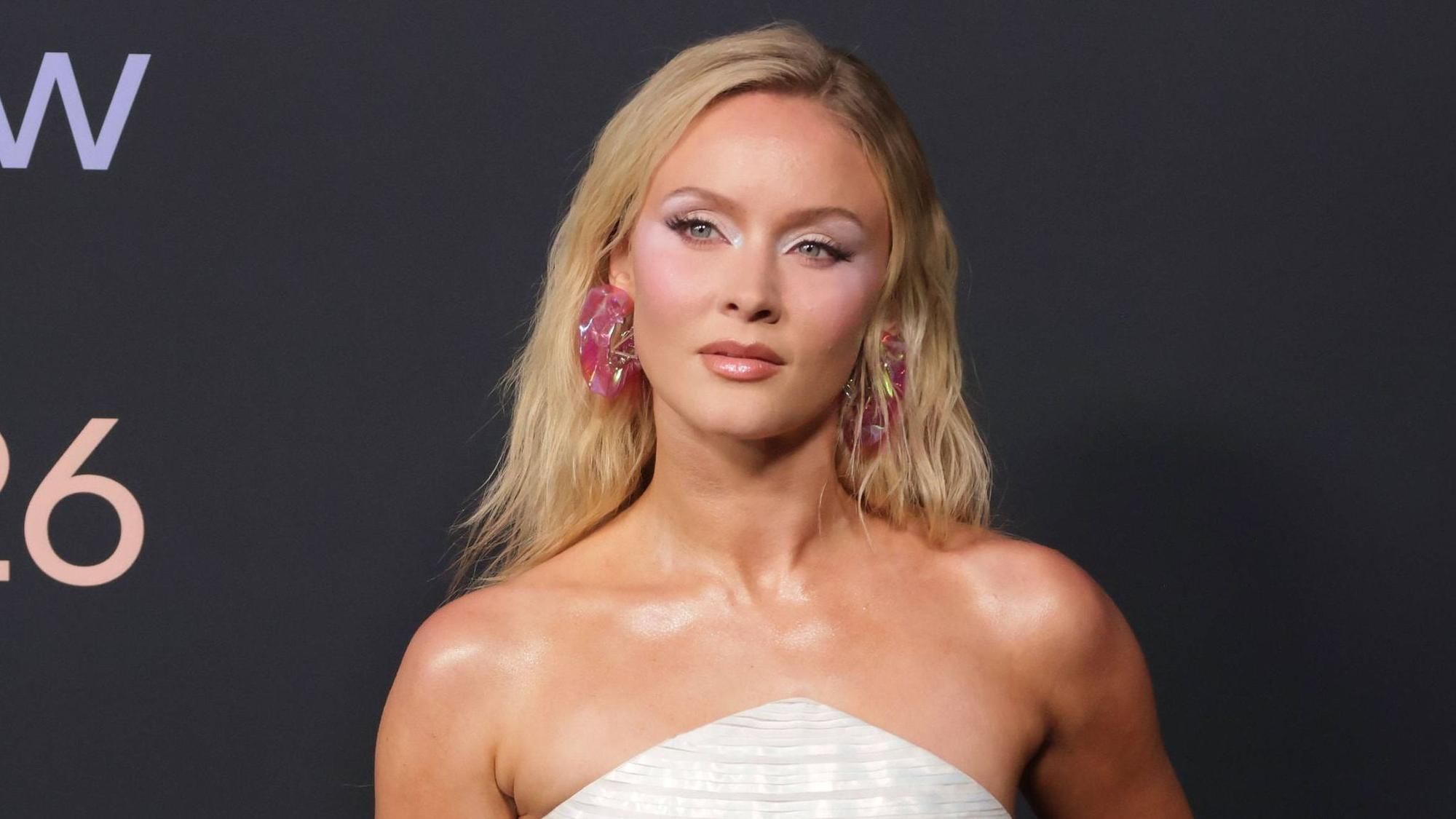 Zara Larsson in weißem Kleid und bunten Accessoires.