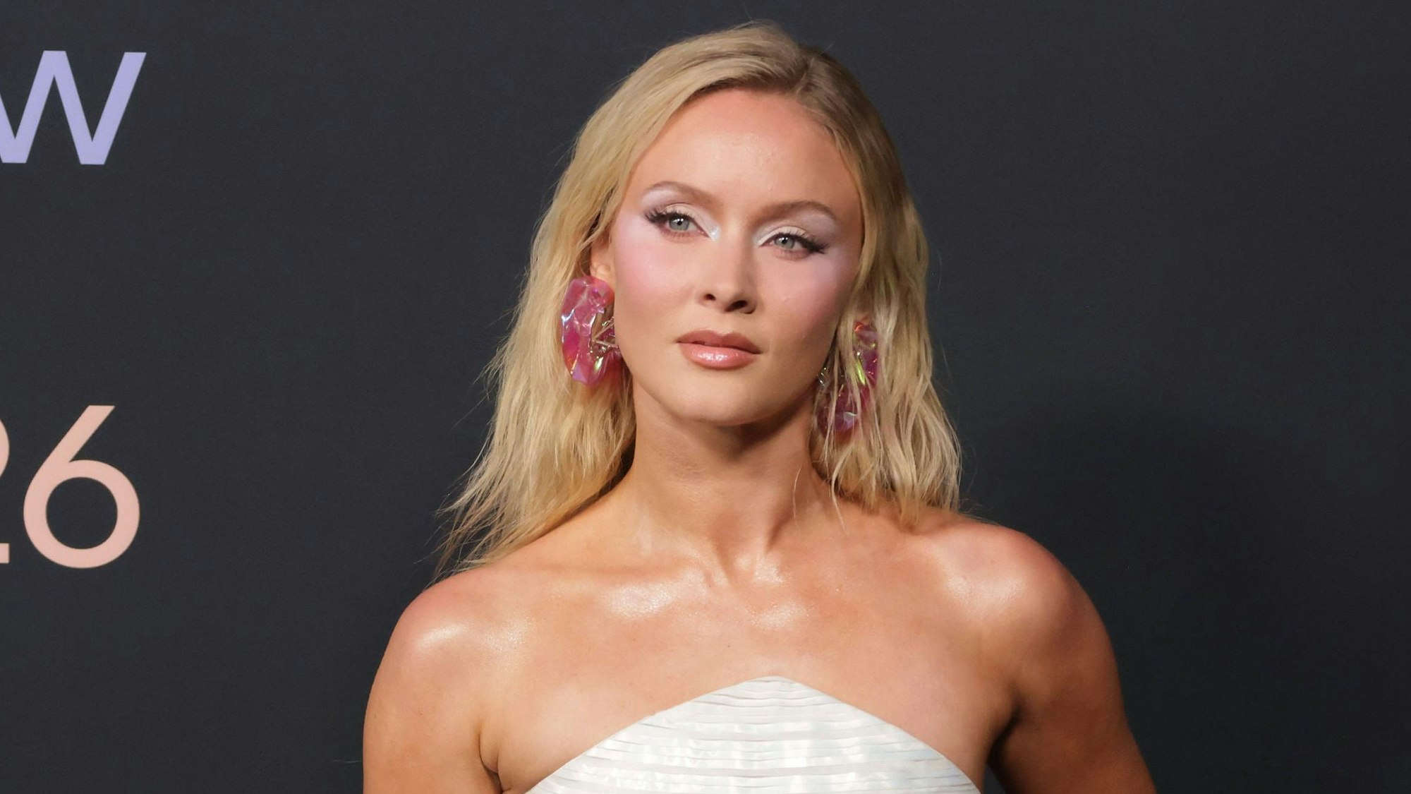 Zara Larsson in weißem Kleid und bunten Accessoires.