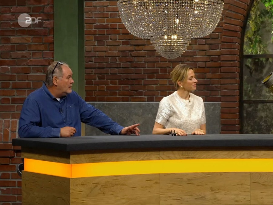 „Das ist doch mal ein Glas!“, war Walter Lehnertz auch ohne Bier angetan von dem Mitbringsel. „Sie sehen aus wie ein Cowboy“, begrüßte Lisa Nüdling den Gast. Kein Wunder, schießlich erinnerte das Mitbringsel in einem Detail an Cowboy-Stiefel. (Bild: ZDF)