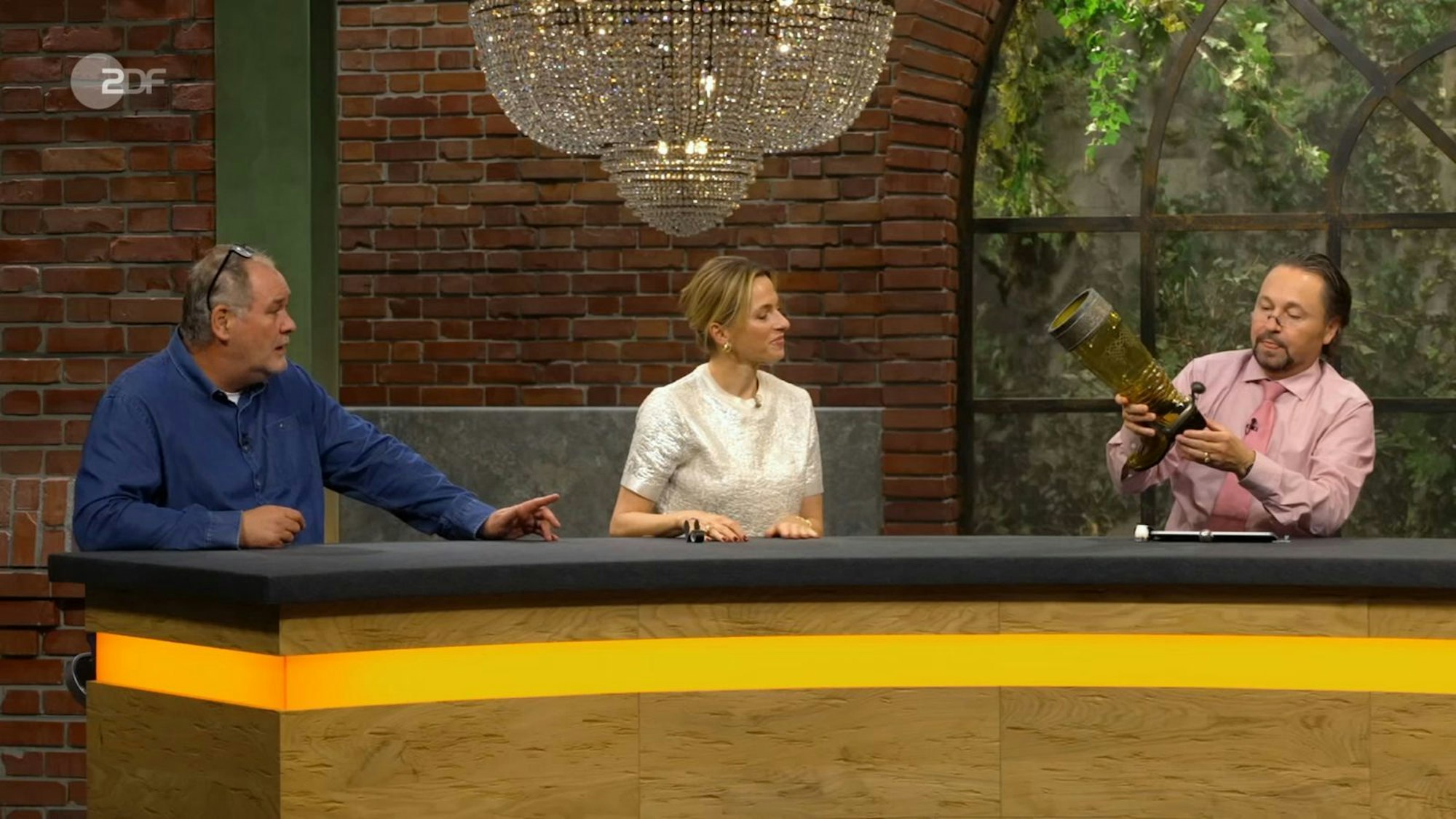 „Das ist doch mal ein Glas!“, war Walter Lehnertz auch ohne Bier angetan von dem Mitbringsel. „Sie sehen aus wie ein Cowboy“, begrüßte Lisa Nüdling den Gast. Kein Wunder, schießlich erinnerte das Mitbringsel in einem Detail an Cowboy-Stiefel. (Bild: ZDF)