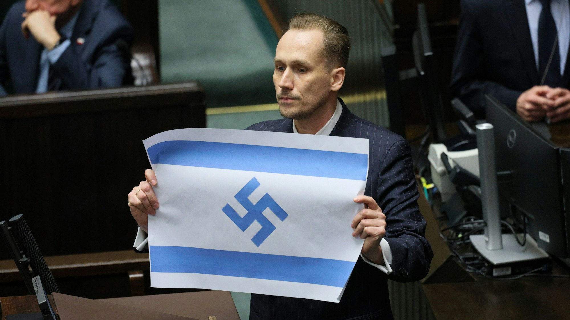 Konrad Berkowicz, Abgeordneter im Sejm in Warschau, Polen, hält eine israelische Flagge mit einem Hakenkreuz.