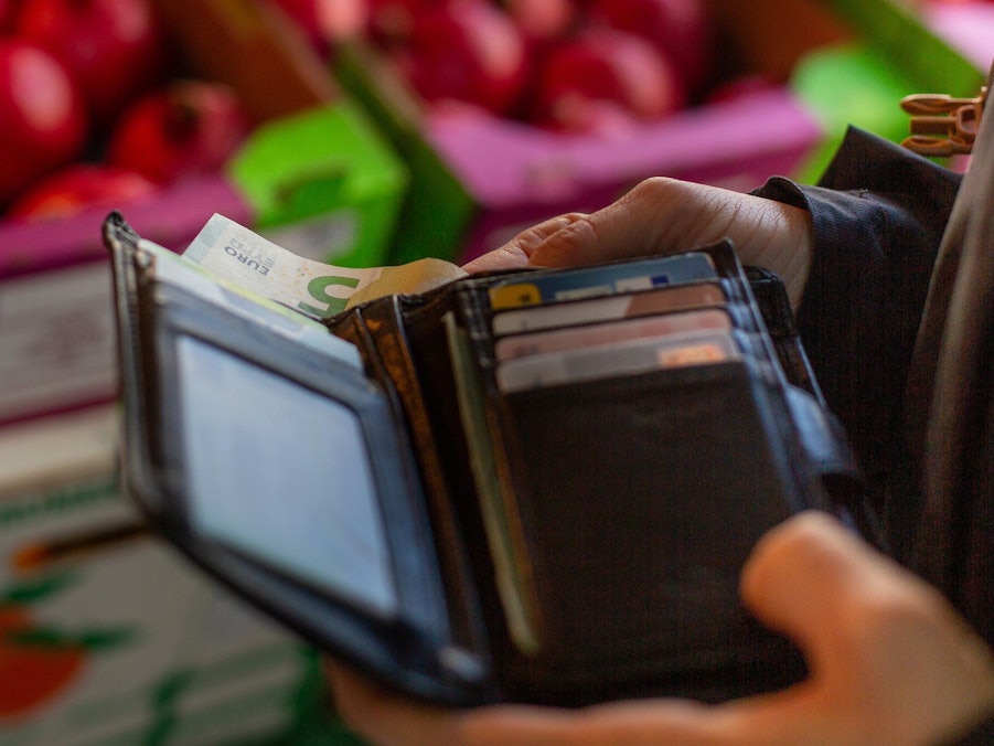 Eine Frau holt eine 5-Euro-Banknote aus ihrem Portemonnaie
