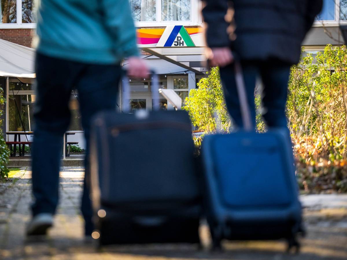 Gäste stehen mit Koffern und Taschen vor einer Jugendherberge