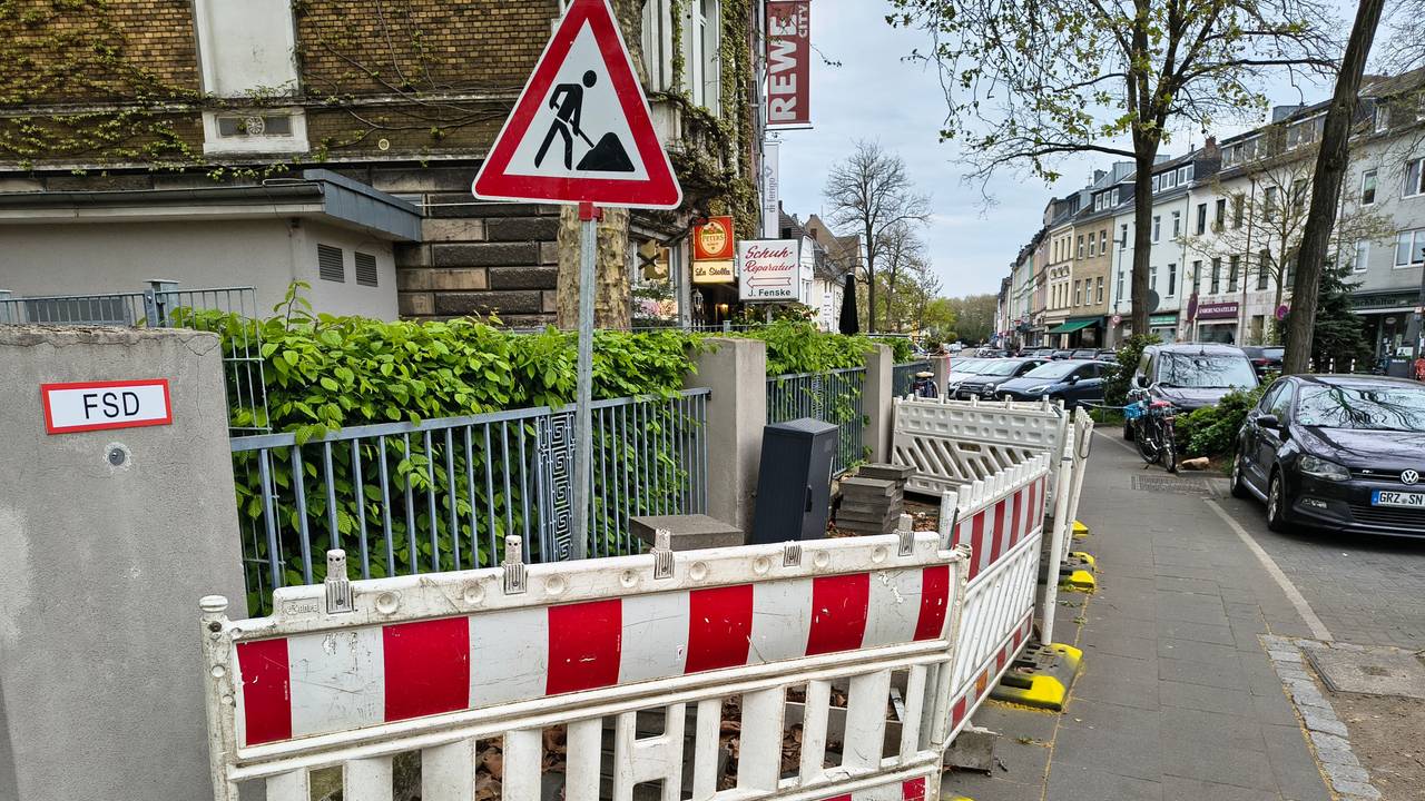Die Dauerbaustelle in Köln-Riehl. Mit gelber Farbe hat ein Anwohner die Füße der Absperrungen markiert.