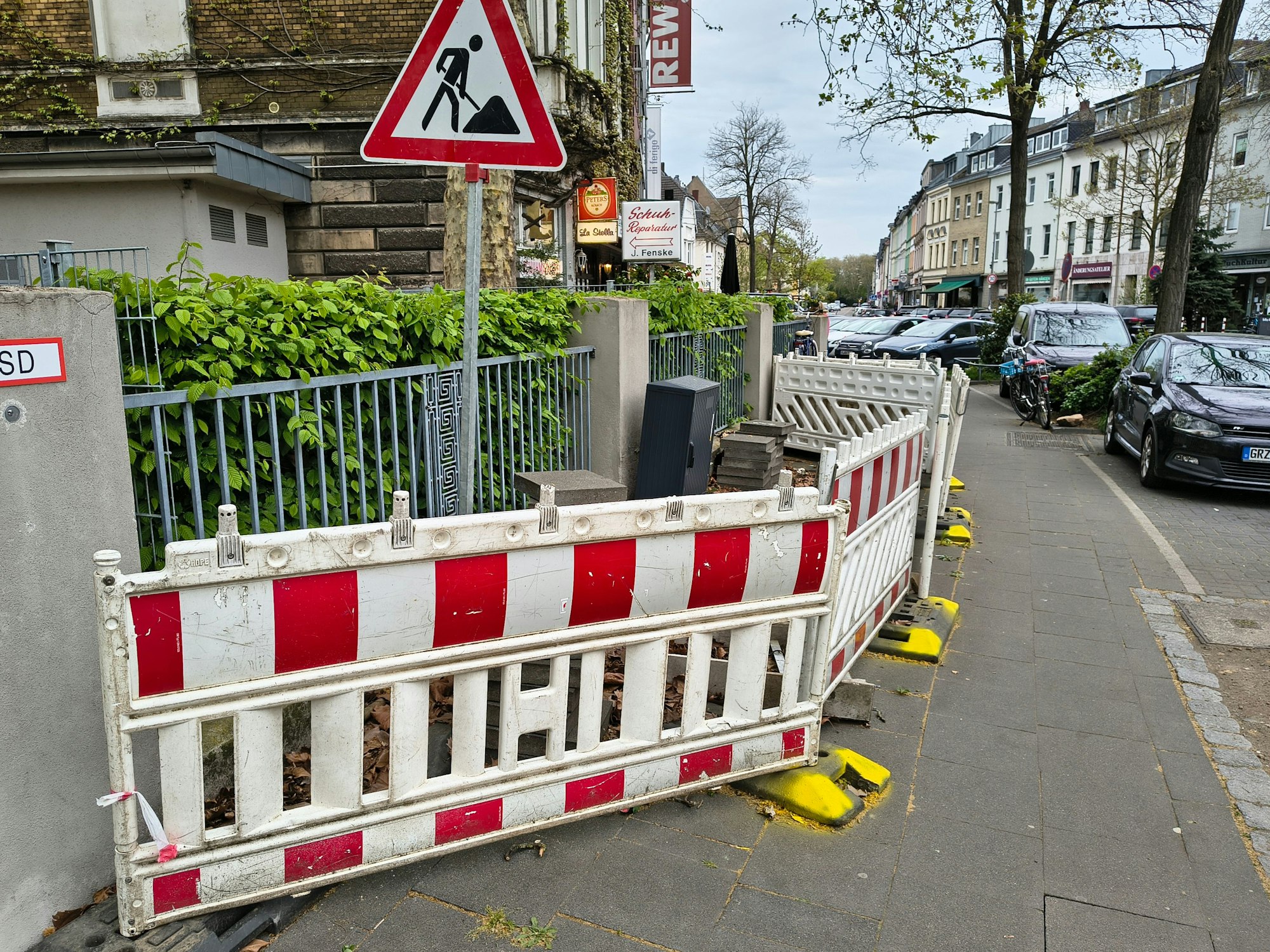 Die Dauerbaustelle in Köln-Riehl. Mit gelber Farbe hat ein Anwohner die Füße der Absperrungen markiert.