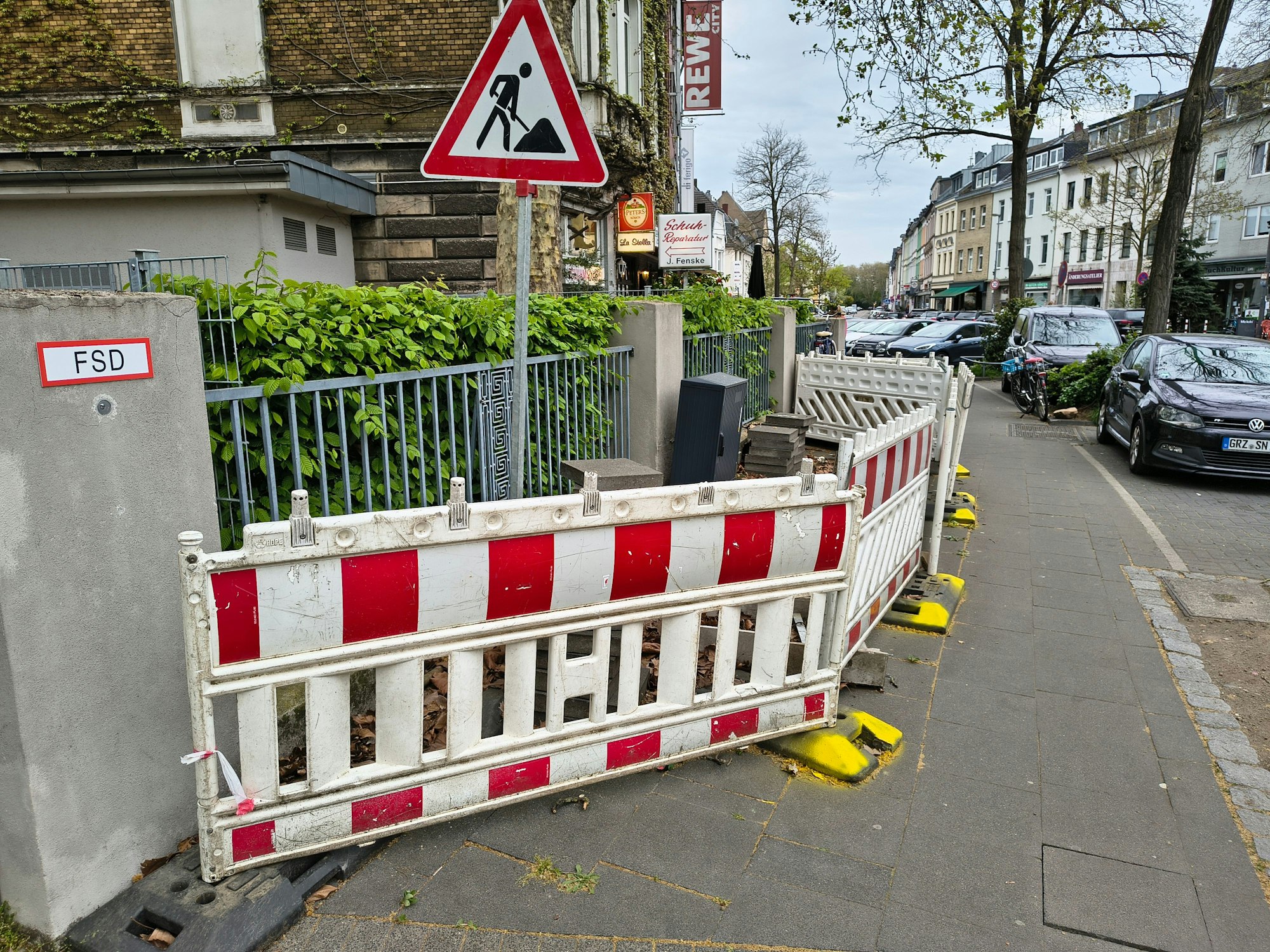 Die Dauerbaustelle in Köln-Riehl. Mit gelber Farbe hat ein Anwohner die Füße der Absperrungen markiert.