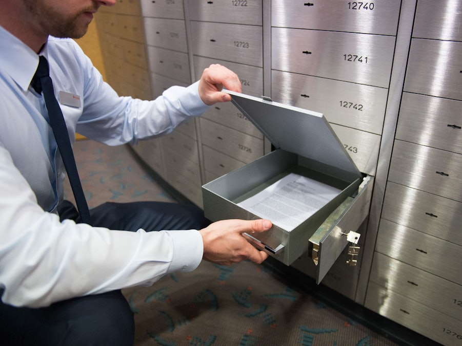 Ein Sparkassenmitarbeiter blickt in ein Bankschließfach