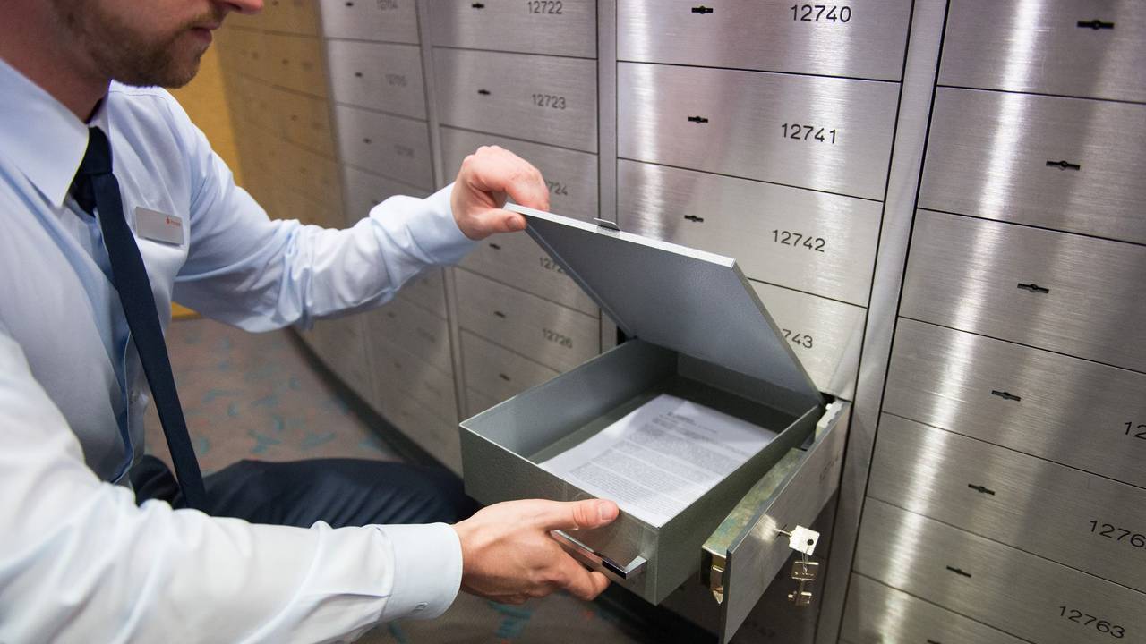 Ein Sparkassenmitarbeiter blickt in ein Bankschließfach