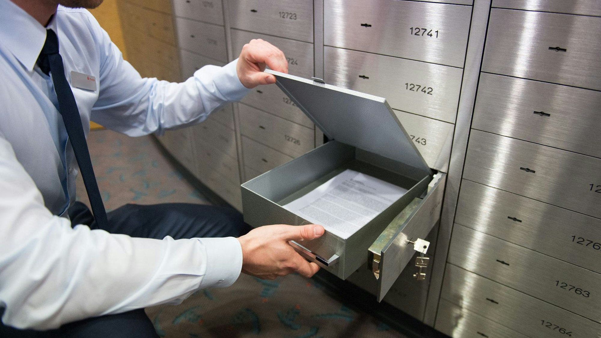 Ein Sparkassenmitarbeiter blickt in ein Bankschließfach
