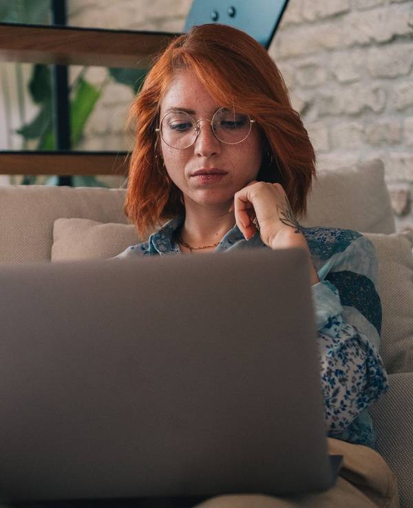 Frau schaut nachdenklich auf einen Laptop