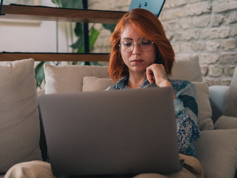 Frau schaut nachdenklich auf einen Laptop