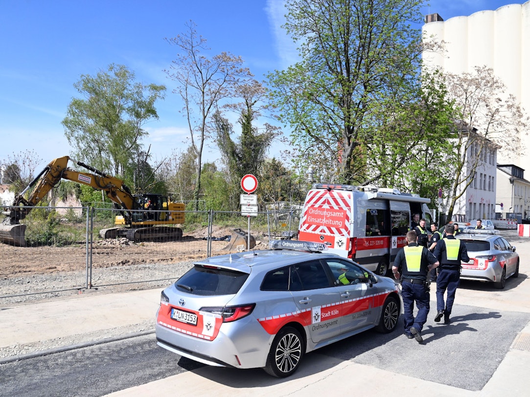 Fahrzeuge der Stadt stehen gegenüber einer Baustelle.