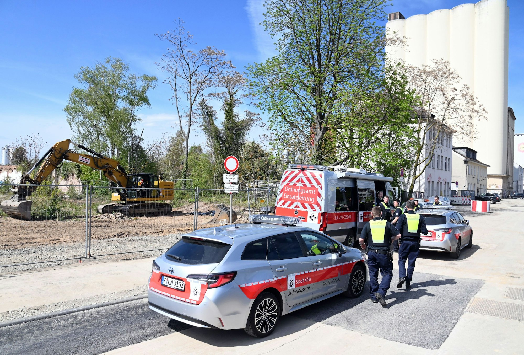 Fahrzeuge der Stadt stehen gegenüber einer Baustelle.