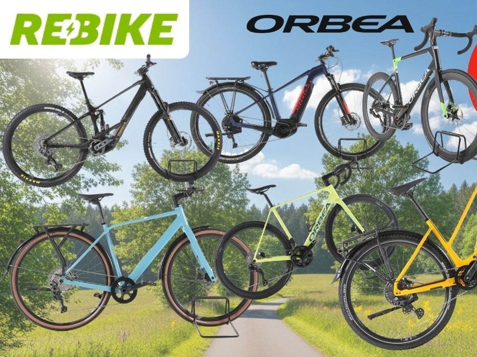 Mehrere refurbished Orbea E-Bikes verschiedener Kategorien – darunter E-Mountainbikes, Trekking-E-Bikes und Gravelbikes – vor einem sonnigen Radweg mit grüner Natur im Hintergrund. Logos von Rebike und Orbea sind zu sehen.