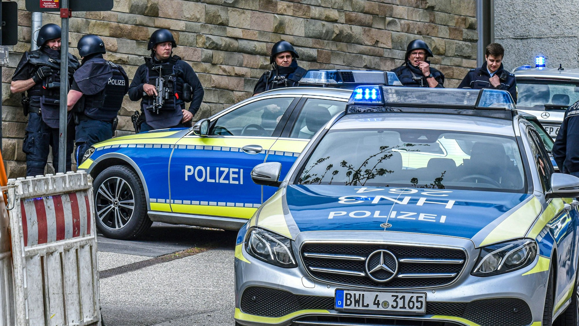 Einsatzkräfte der Polizei und Polizeifahrzeuge mit Blaulicht