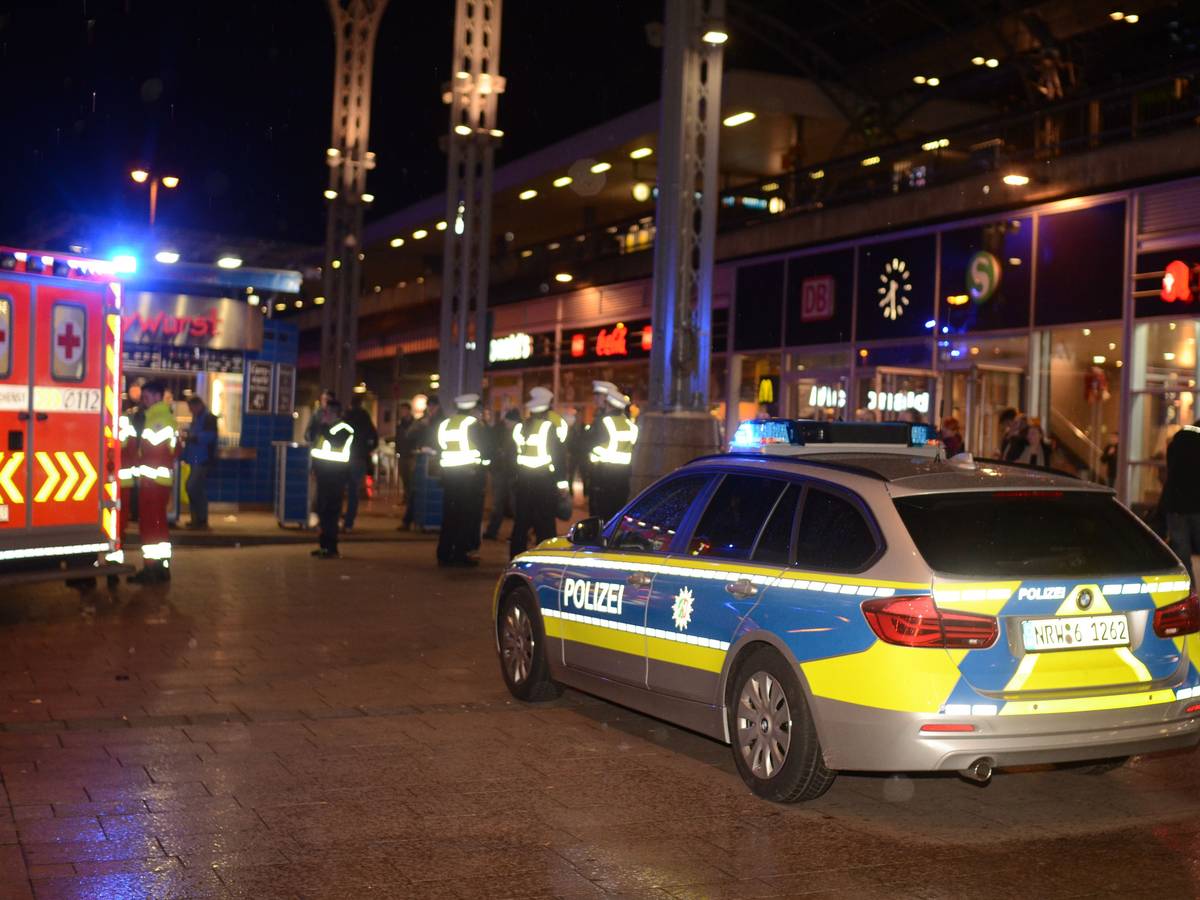 Polizeikräfte und ein Streifenwagen stehen nachts am Kölner Hauptbahnhof.